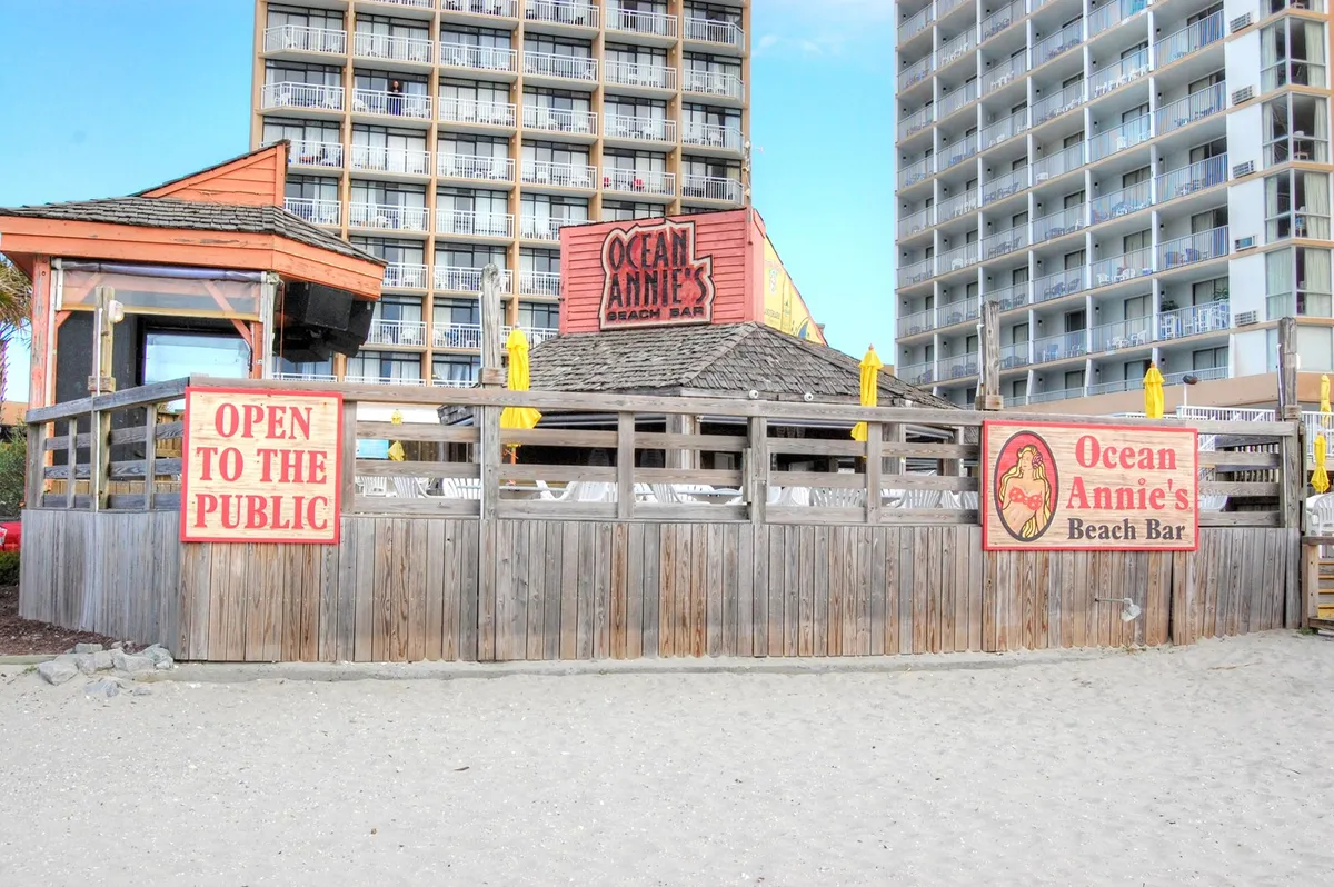 Here, the entrance to Ocean Annie’s Beach Bar is showcased with inviting outdoor seating and prominent signage. The relaxed environment suggests socializing, sunset drinks, and lively gatherings by the coast.