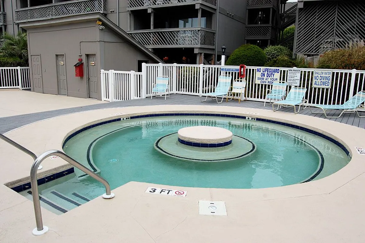 A tranquil pool area with a hot tub and lounge chairs set up for relaxation and socializing. The space is designed for both unwinding solo or sharing moments with friends and family, suggesting a comfortable environment for evening gatherings or post-beach relaxation.