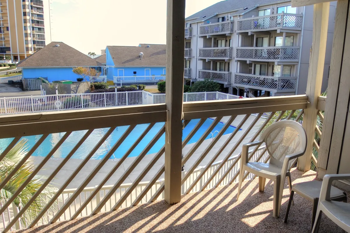 The image focuses on the pool area, visible balcony railing, and a single chair set for relaxing. The perspective hints at a tranquil morning or peaceful afternoon, with inviting pool waters and open spaces designed for sunbathing, reading, or socializing outdoors.